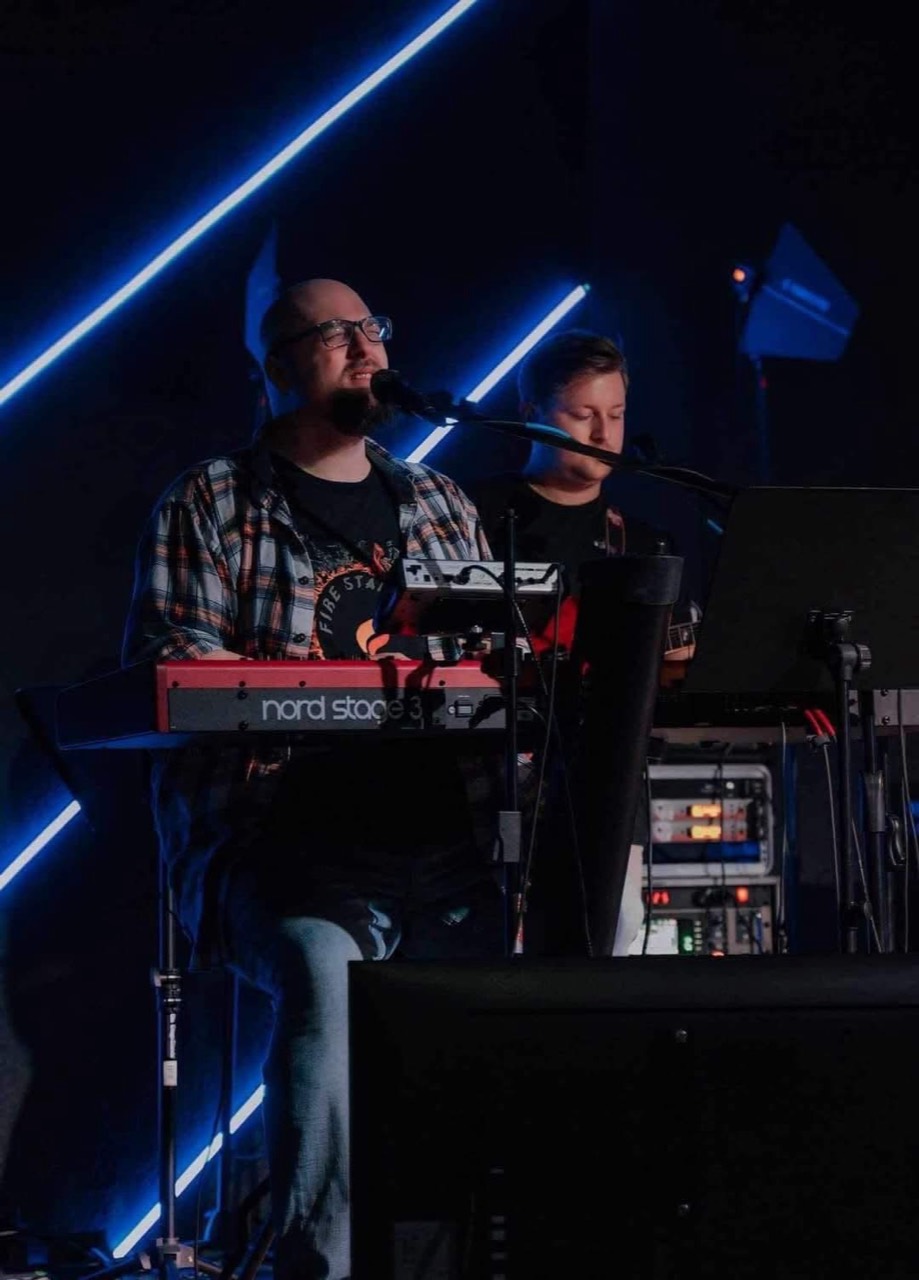 Thomas and a young family member together at the keyboard during worship